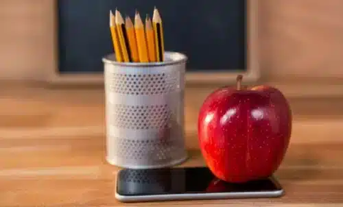 Arbeitsplatz mit Apfel, Stiften und Handy auf dem Schreibtisch